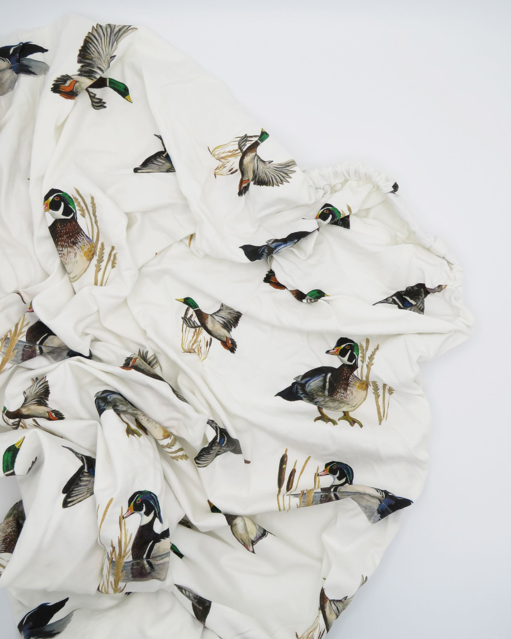 Soft cotton crib sheet with playful diving ducks pattern, perfect for a cozy duck-themed nursery.