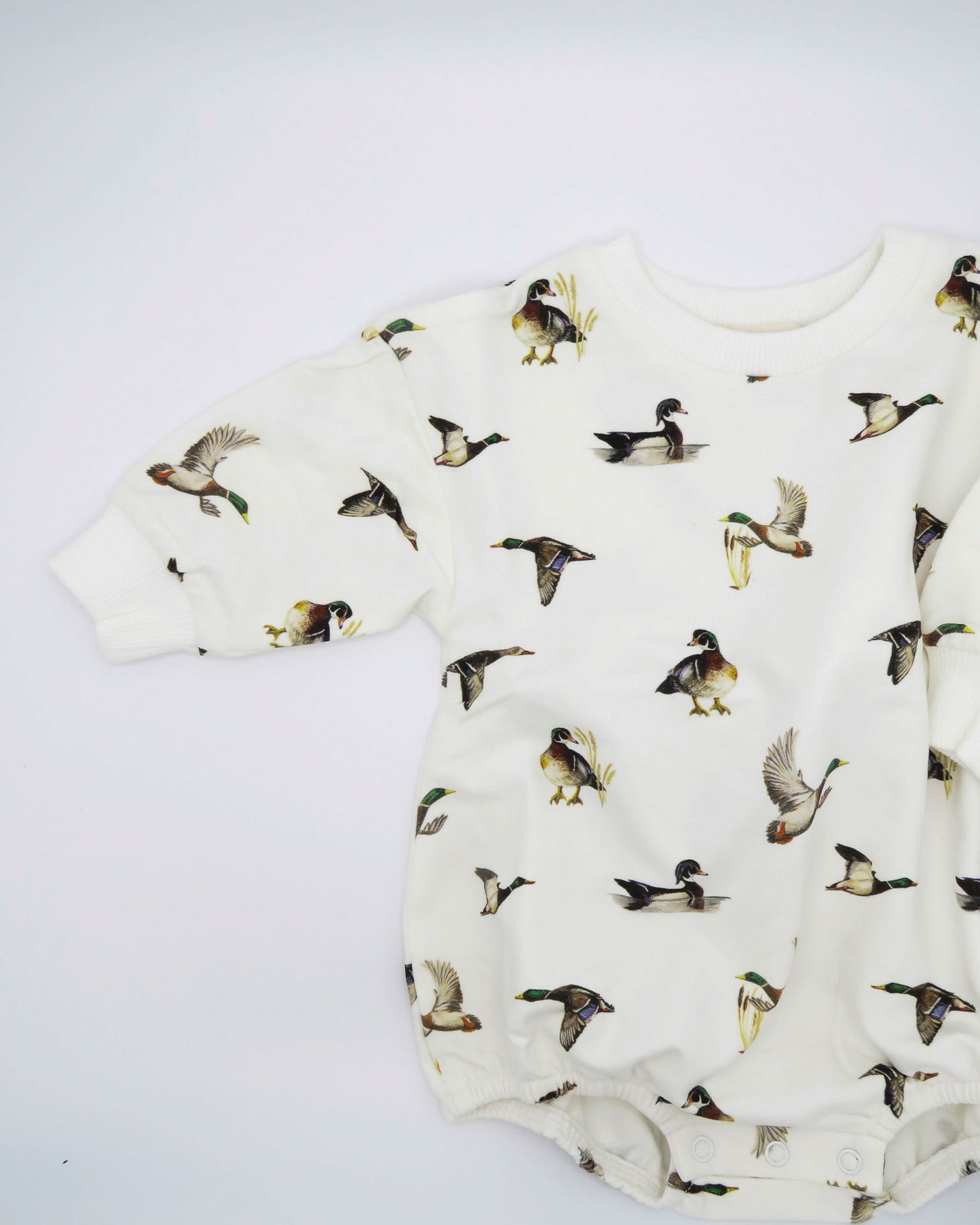 Diving Ducks print Sweatshirt Romper printed on soft white fabric. Perfect for indoors and outdoors, worn by a toddler.