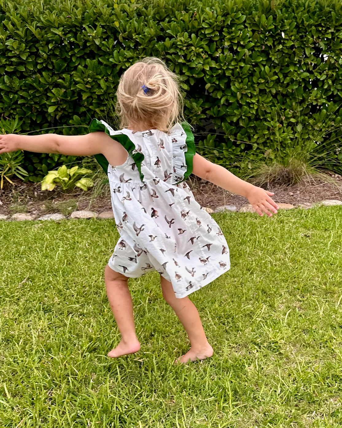 Diving Ducks flutter dress printed on soft white fabric. Perfect for indoors and outdoors. Worn by a young girl outdoor.