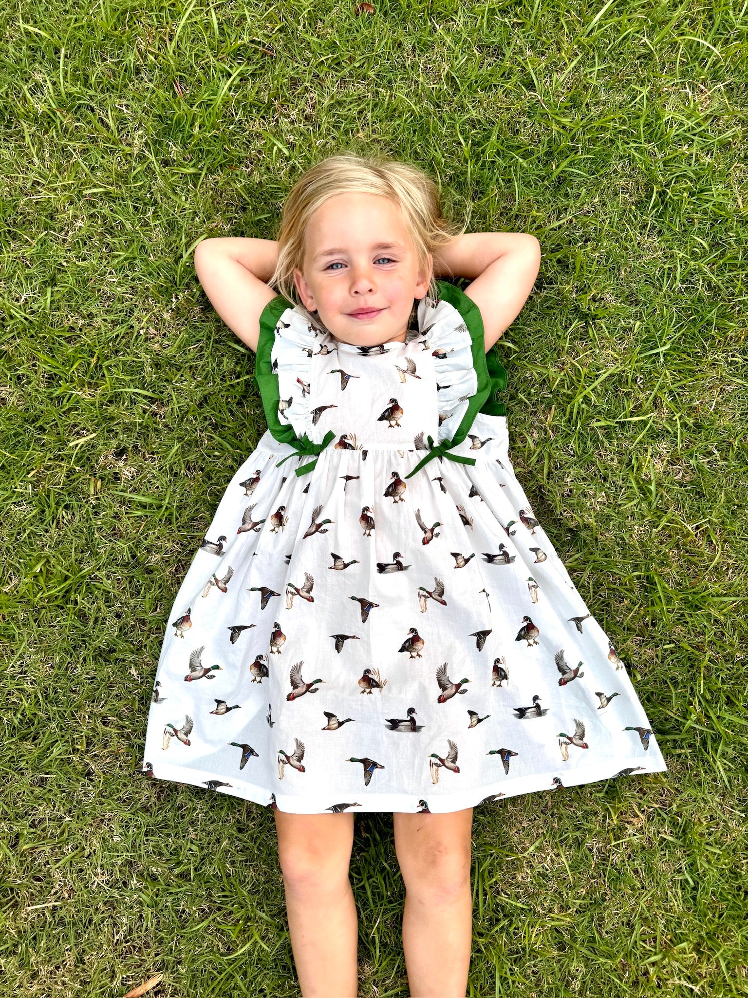 Diving Ducks flutter dress printed on soft white fabric. Perfect for indoors and outdoors. Worn by a young girl outdoor.