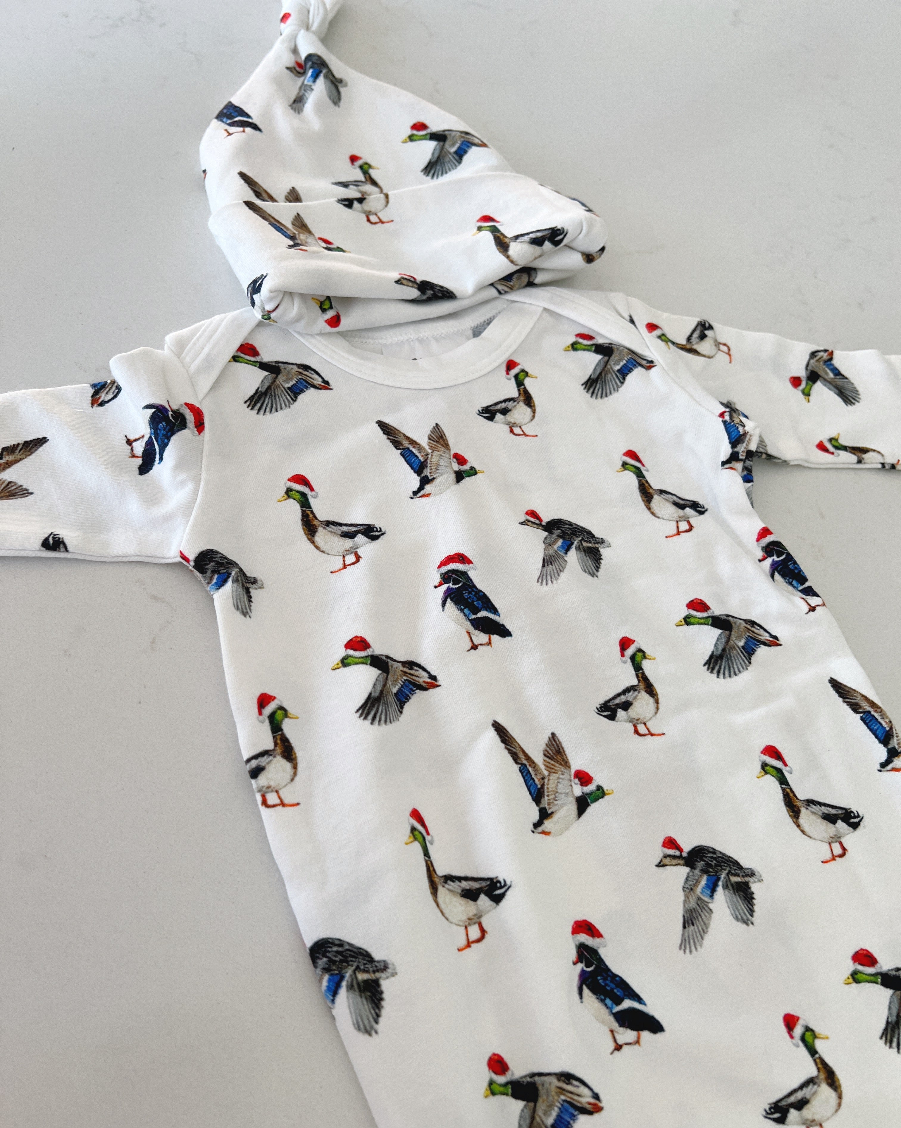A cute newborn outfit featuring a print of ducks with Santa hat.