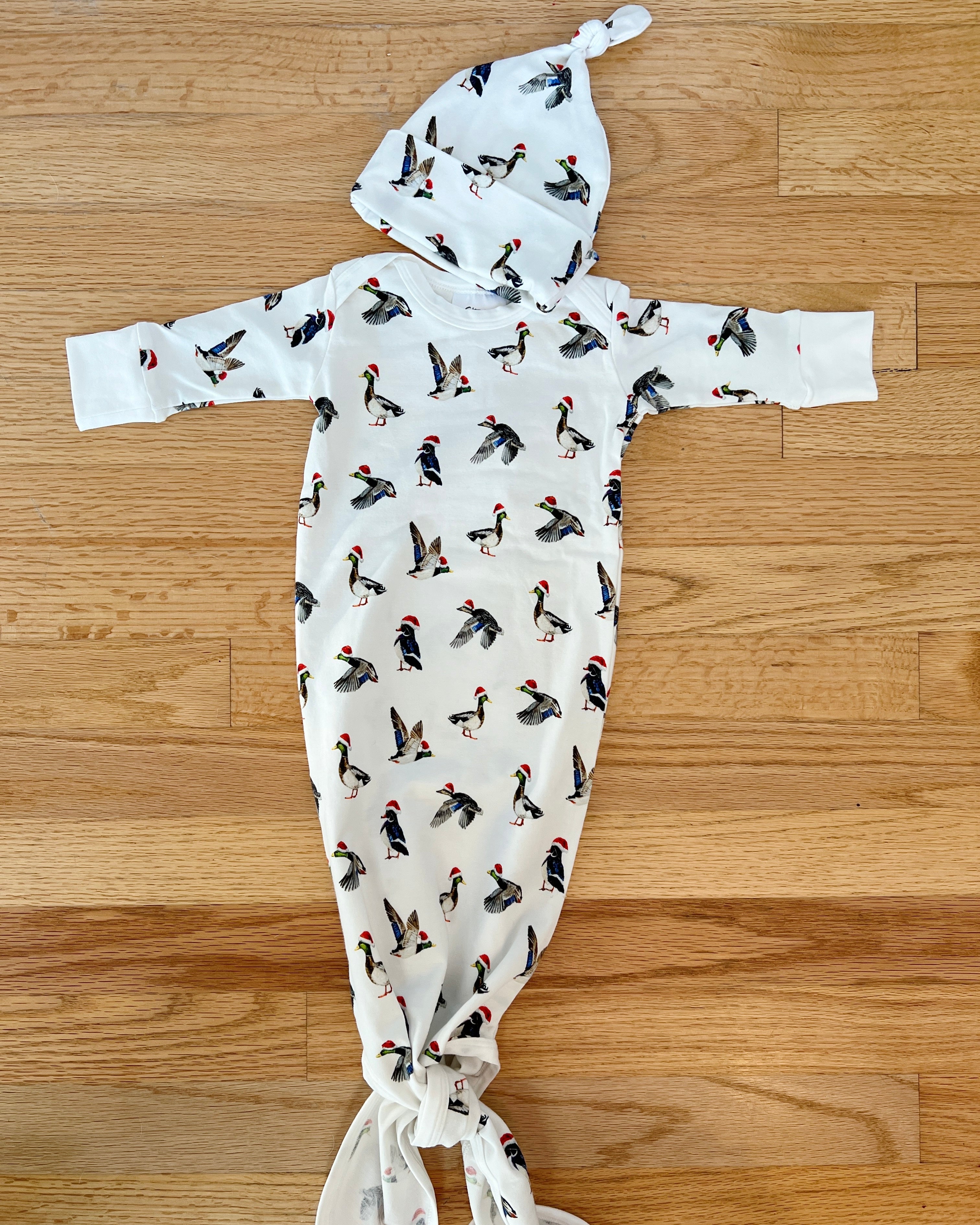 A cute newborn outfit featuring a print of ducks with Santa hat.