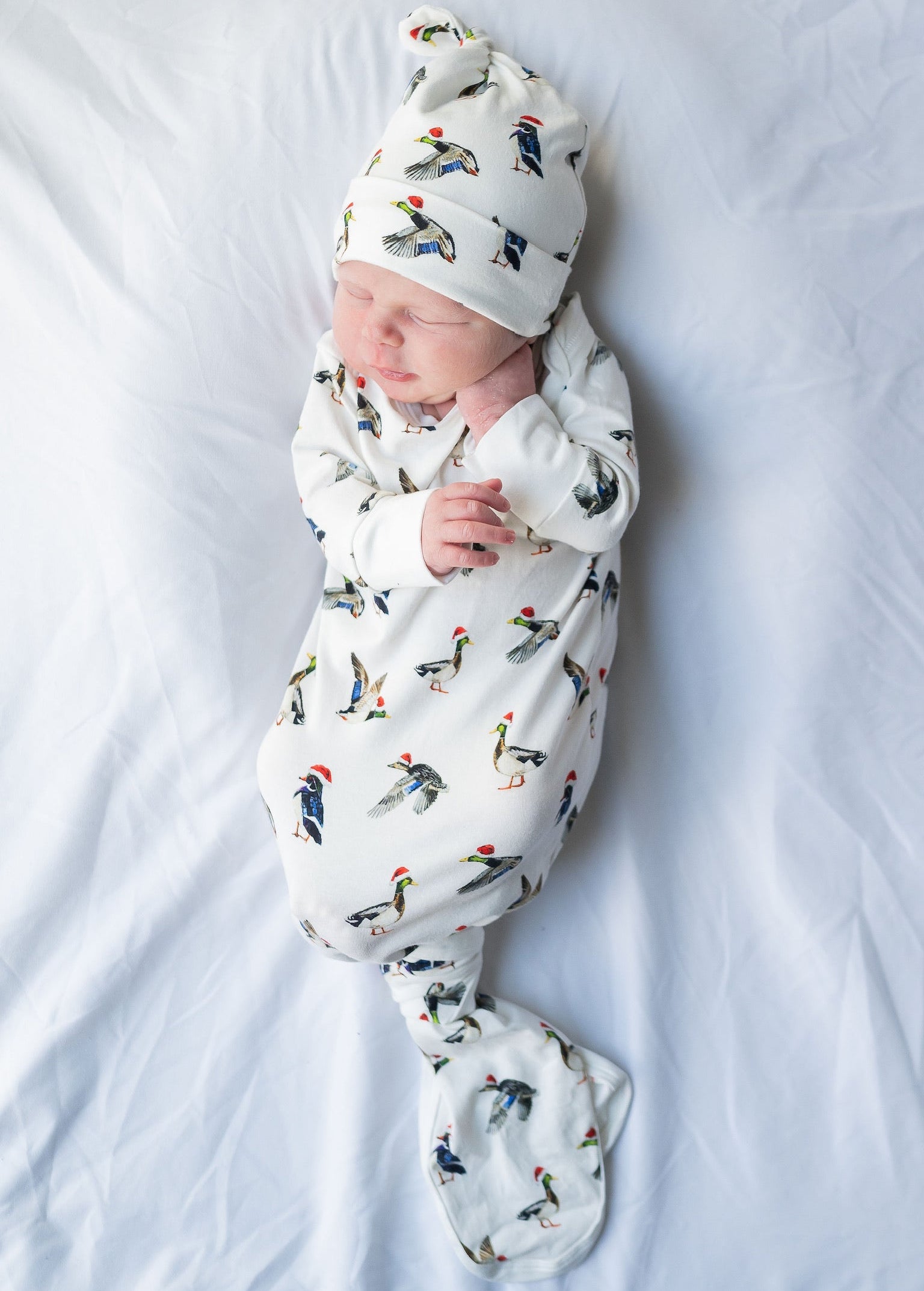 A cute newborn outfit featuring a print of ducks with Santa hat.