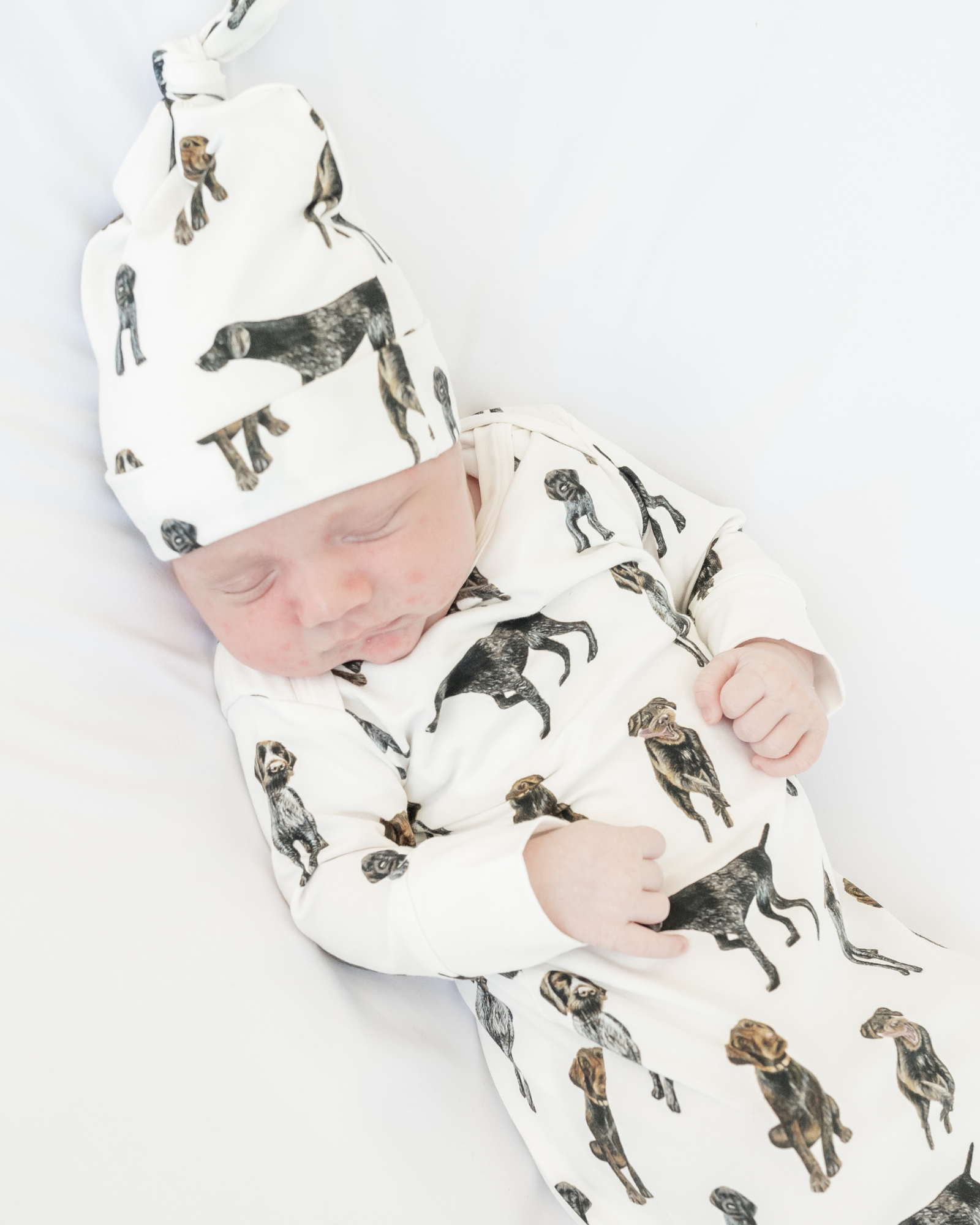 German Wirehaired Pointer print newborn gown and matching hat set for baby boys and girls. GWP dogs printed on soft white fabric, worn by a baby.