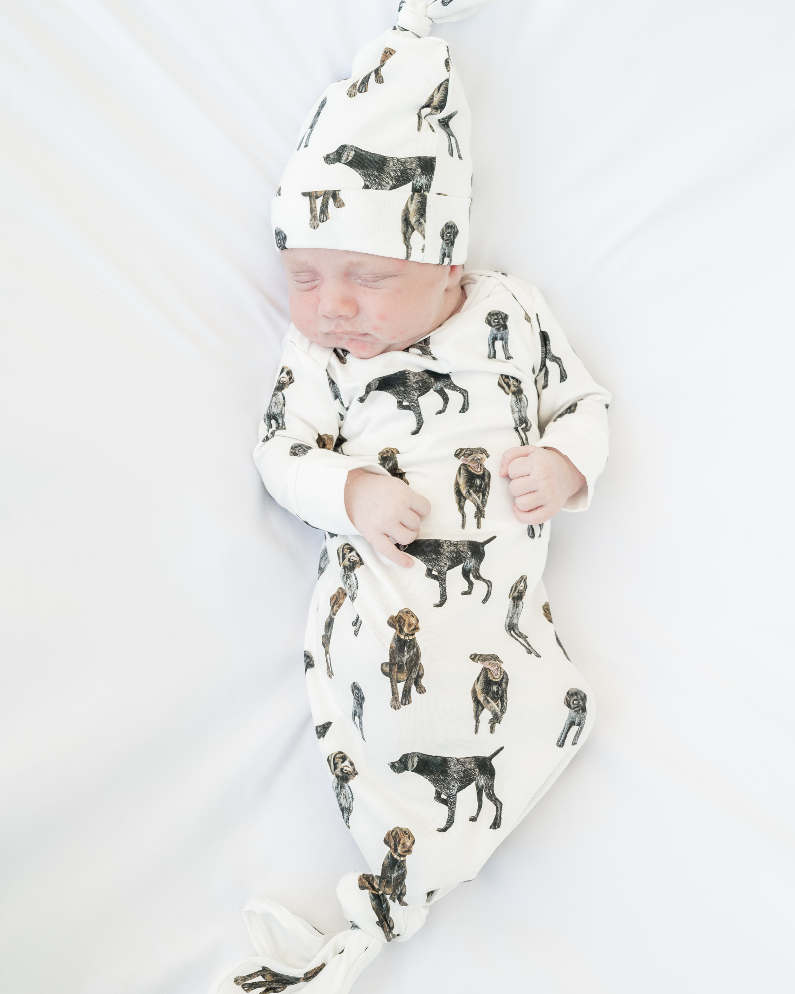 German Wirehaired Pointer print newborn gown and matching hat set for baby boys and girls. GWP dogs printed on soft white fabric, worn by a baby.