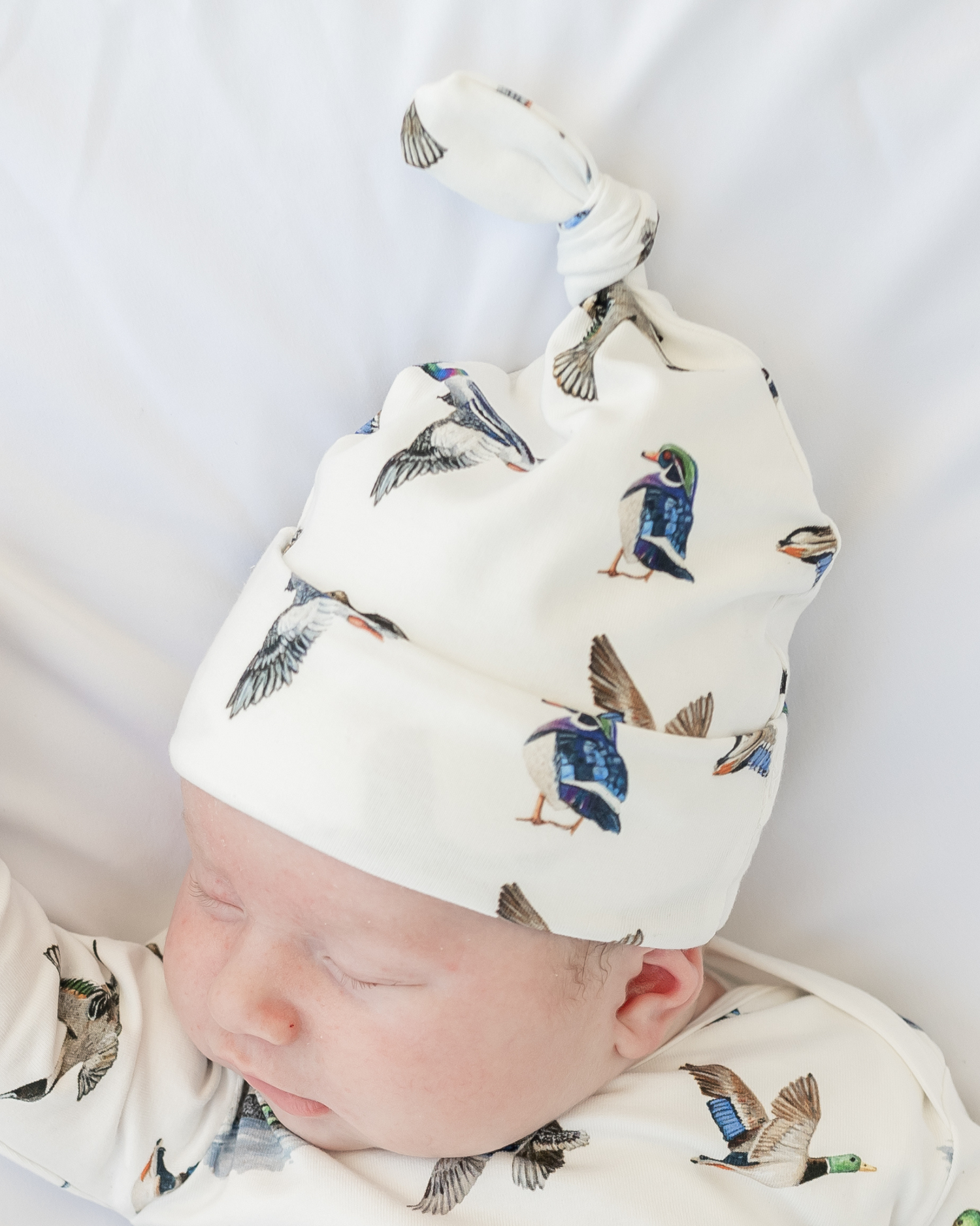 Baby wearing a white hat with duck pattern - Lucky Ducks newborn hat