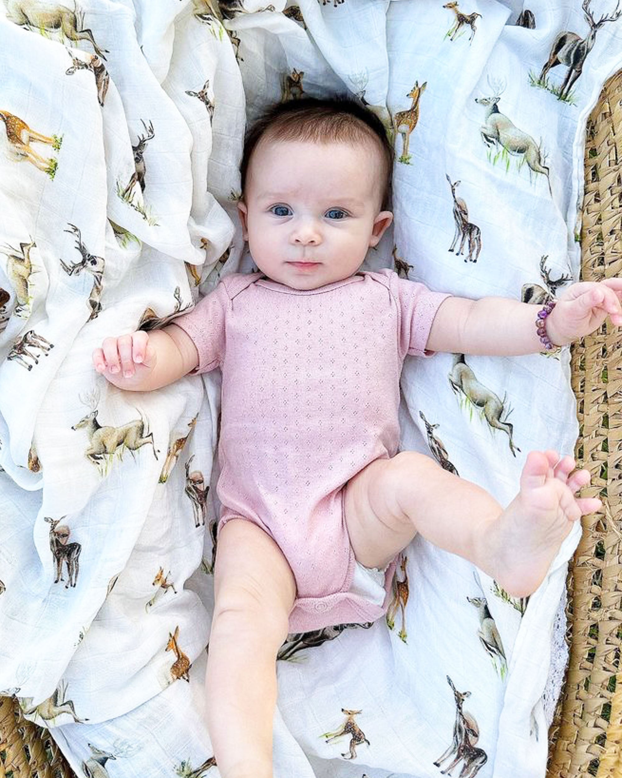 Little Fawn, Big Yawn Deer hand-painted swaddle with bucks, does, and fawn, perfect for your little sportsman or sportswoman, made from soft 30% white organic cotton and 70% bamboo blend. Used by a baby.