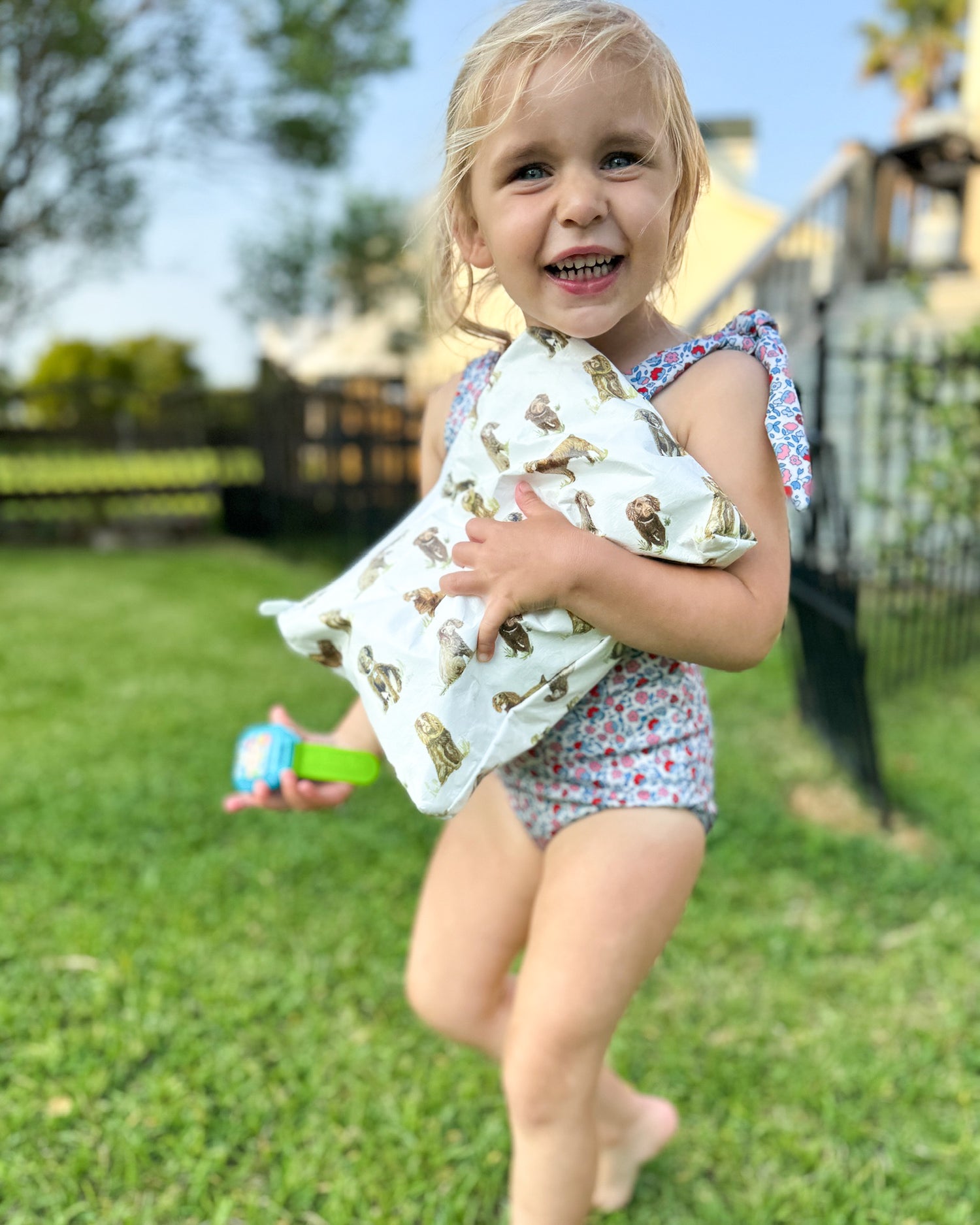 A child holding a water-resistant white pouch with a Beaufort Boykin dog print, standing on grass.