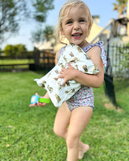 A child holding a water-resistant white pouch with a Beaufort Boykin dog print, standing on grass.