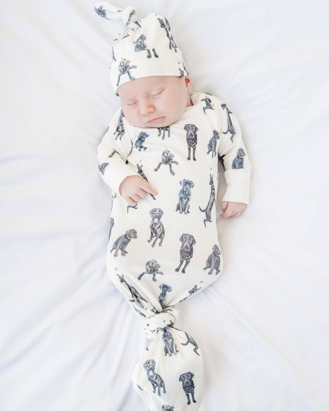 Newborn gown and matching hat featuring Black Labs print worn by a sleeping baby, perfect for baby showers and dog-loving parents