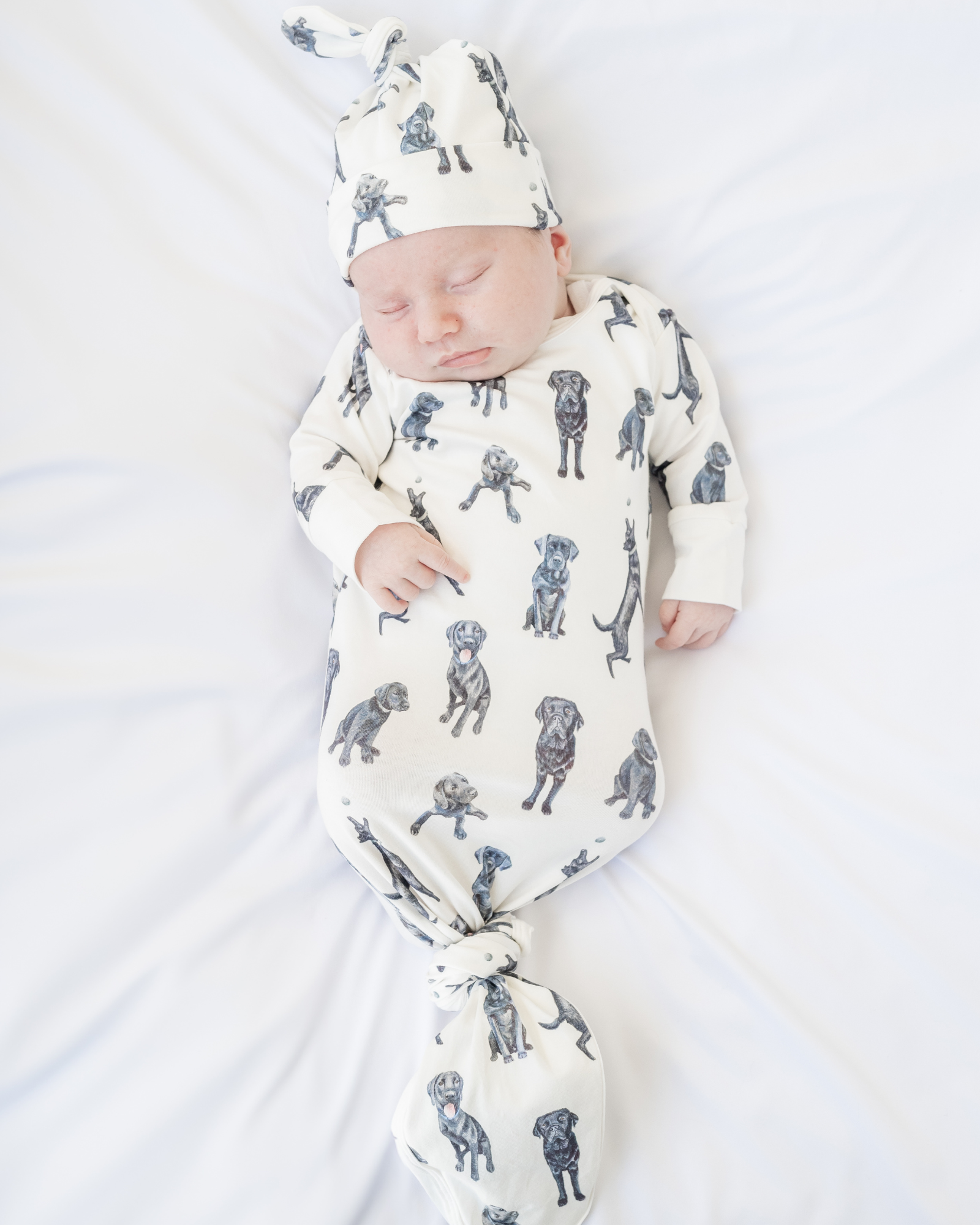 Newborn gown and matching hat featuring Black Labs print worn by a sleeping baby, perfect for baby showers and dog-loving parents