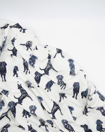 Fitted Black Lab crib sheet featuring adorable Black Labrador designs, crafted for durability and softness, printed on gentle white fabric—perfect for both cribs and toddler beds.