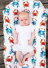 A newborn swaddled in a blanket with vibrant hand-painted crab patterns.
