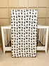 A crib sheet with a pattern of chocolate labs, displayed in front of a crib.