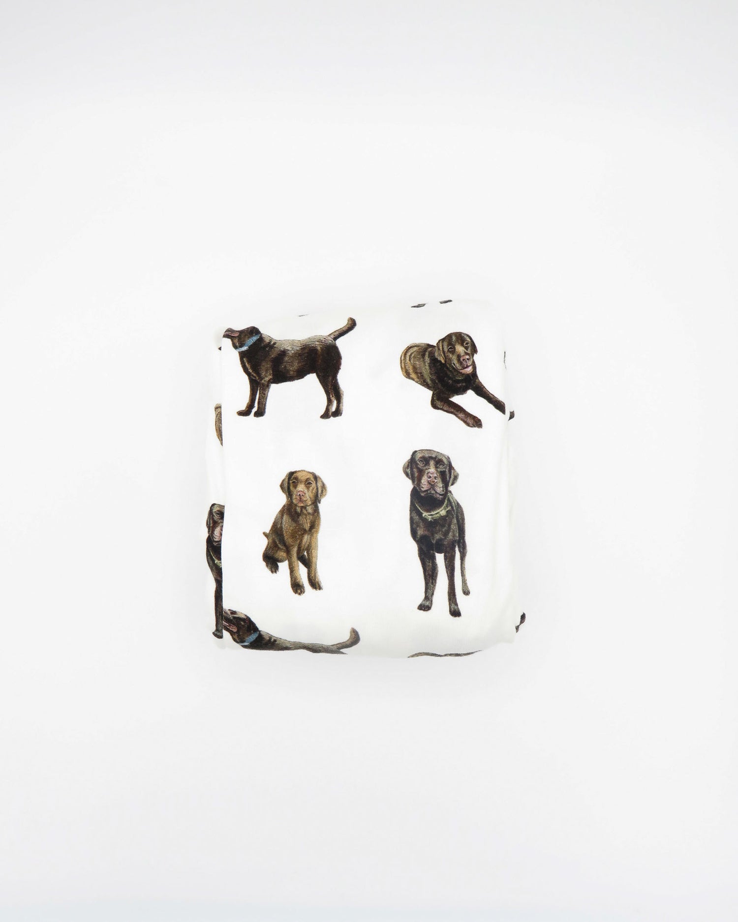 A white crib sheet with a chocolate labrador retriever print, displayed and folded on a white background.