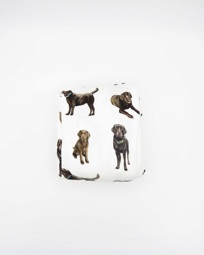 A white crib sheet with a chocolate labrador retriever print, displayed and folded on a white background.