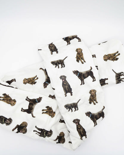 A white crib sheet with a chocolate labrador retriever print, displayed and folded on a white background.