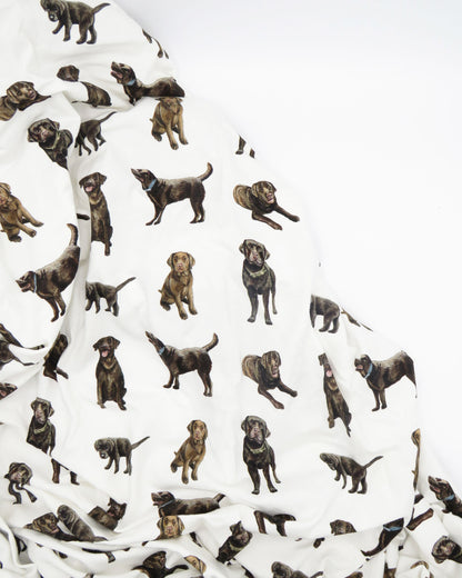A white crib sheet with a chocolate labrador retriever print, displayed on a white background.