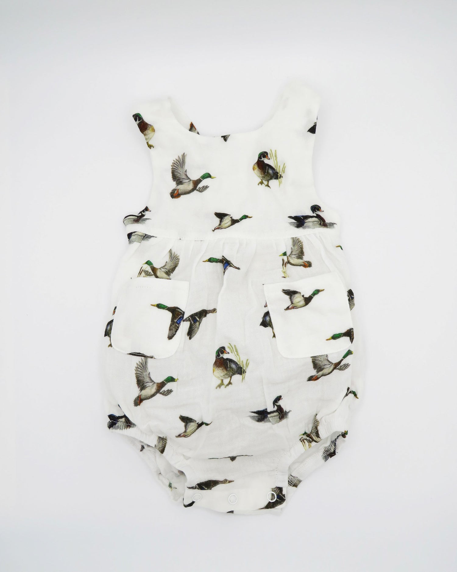 Diving ducks Best organic cotton sunsuit for kids in vibrant spring pattern. Diving Ducks printed on soft white fabric, worn by a little girl outdoors.