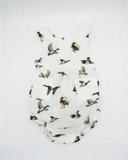 Diving ducks Best organic cotton sunsuit for kids in vibrant spring pattern. Diving Ducks printed on soft white fabric, worn by a little girl outdoors.