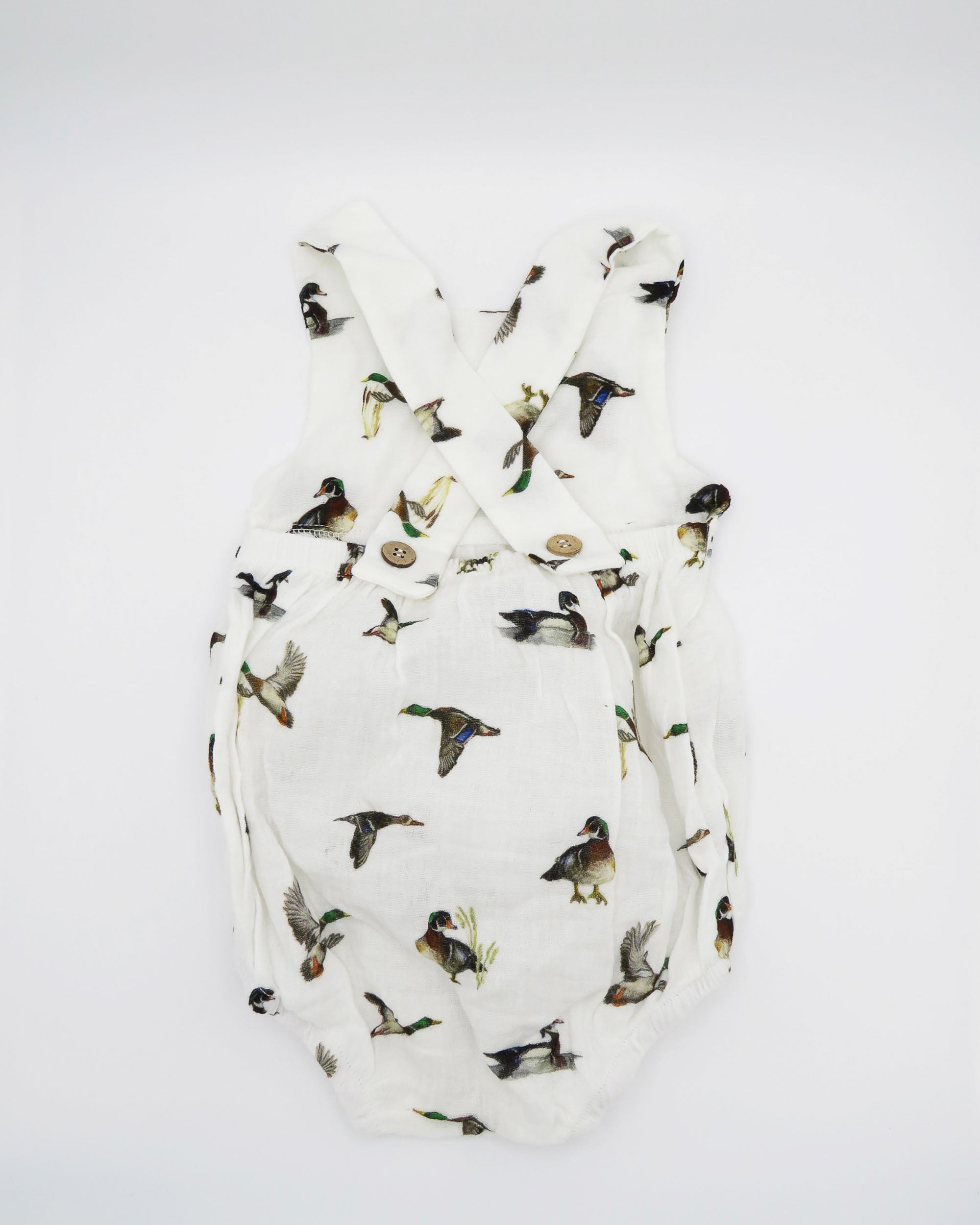 Diving ducks Best organic cotton sunsuit for kids in vibrant spring pattern. Diving Ducks printed on soft white fabric, worn by a little girl outdoors.