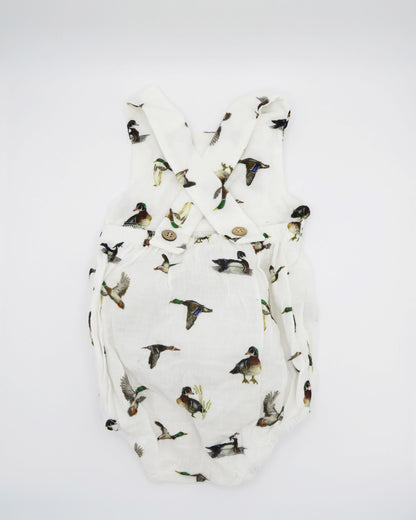 Diving ducks Best organic cotton sunsuit for kids in vibrant spring pattern. Diving Ducks printed on soft white fabric, worn by a little girl outdoors.
