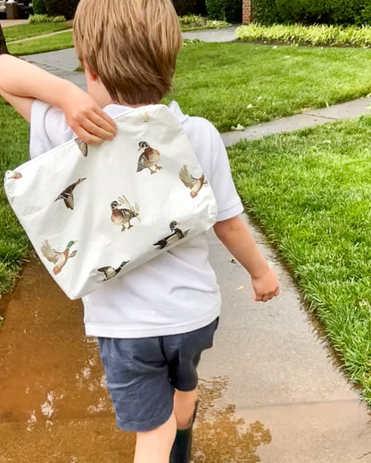 Close-up of a diving ducks pattern water-resistant white pouch showcasing its unique pattern and craftsmanship. Used by young boy outdoors for keeping his toys safe from the rain.