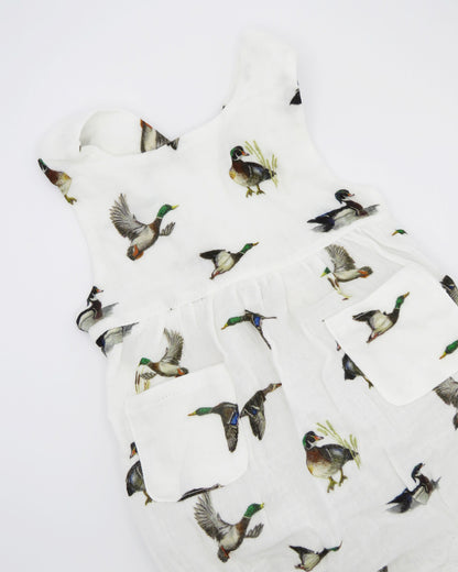 Diving ducks Best organic cotton sunsuit for kids in vibrant spring pattern. Diving Ducks printed on soft white fabric, worn by a little girl outdoors.