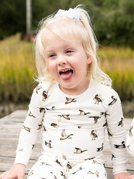 Unisex loungewear or sleepwear featuring a Diving Ducks print on soft white fabric. Kids’ pajamas worn by a little girl. Perfect for both indoor and outdoor wear.