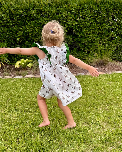 Diving Ducks flutter dress printed on soft white fabric. Perfect for indoors and outdoors. Worn by a young girl outdoor.