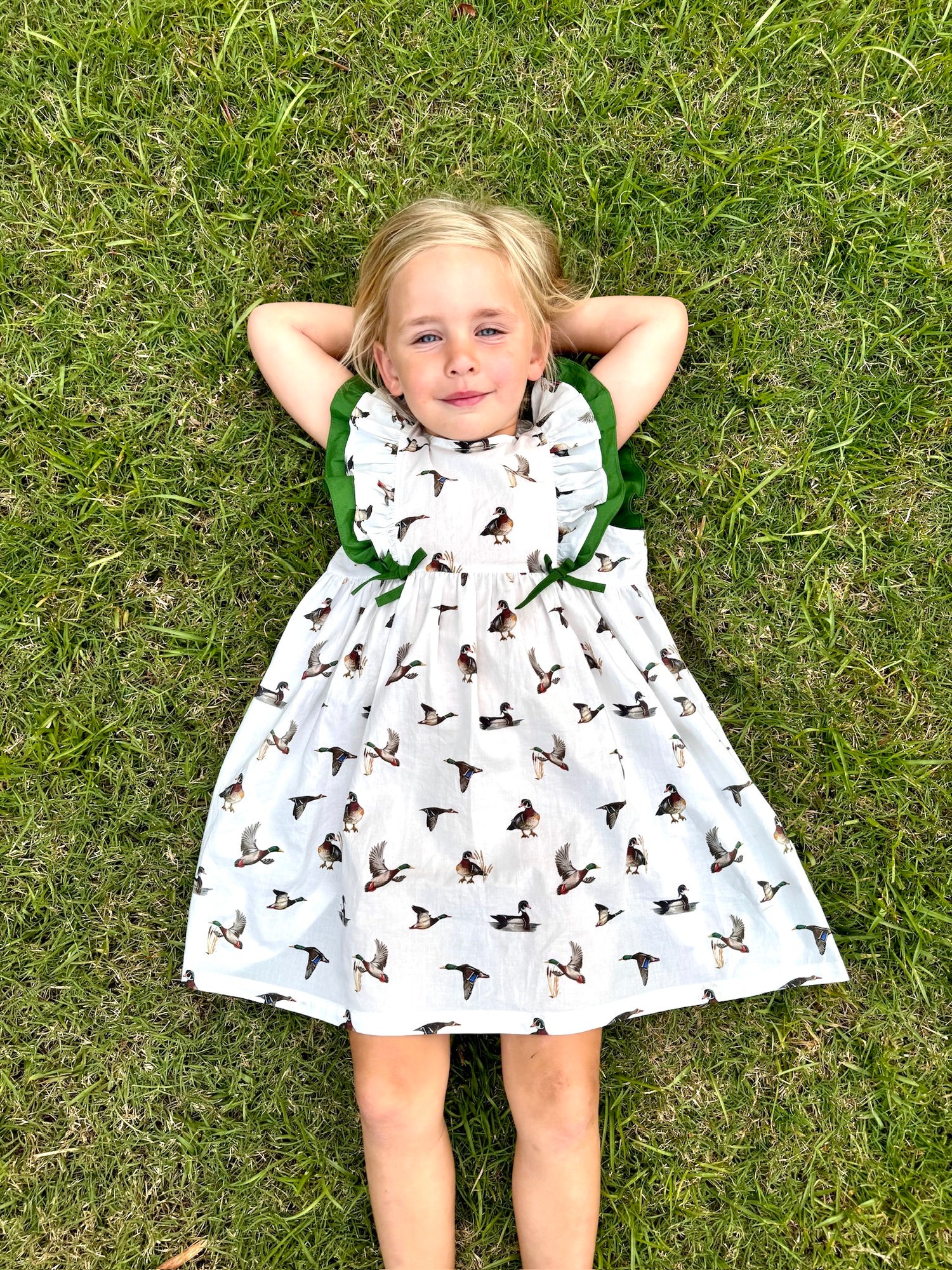 Diving Ducks flutter dress printed on soft white fabric. Perfect for indoors and outdoors. Worn by a young girl outdoor.
