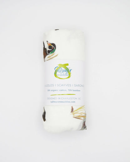 Vibrant watercolor diving ducks pattern swaddle, perfect for wrapping newborns in style and comfort. The soft white fabric features an adorable diving ducks print. Your baby will look precious wrapped in this cute swaddle, ideal for those first special moments and a thoughtful addition to the hospital bag.