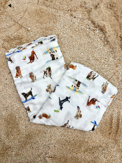 Dog Days of Summer pattern swaddle displayed folded and flat on beach sand.