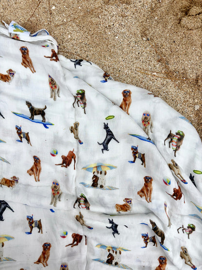 Dog Days of Summer pattern swaddle displayed on beach sand.