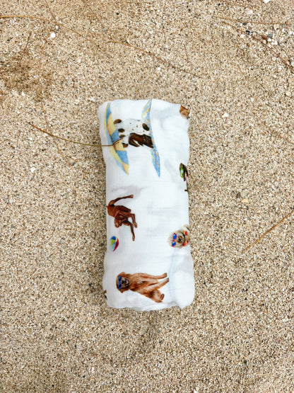 Dog Days of Summer pattern swaddle displayed rolled on beach sand.