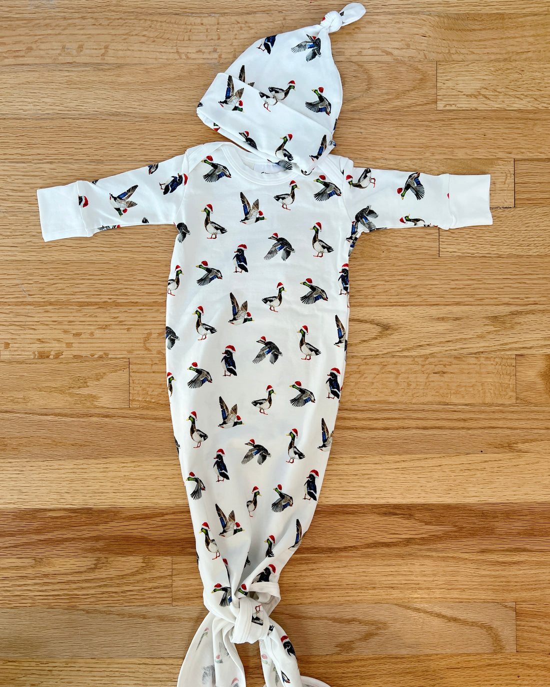A cute newborn outfit featuring a print of ducks with Santa hat.
