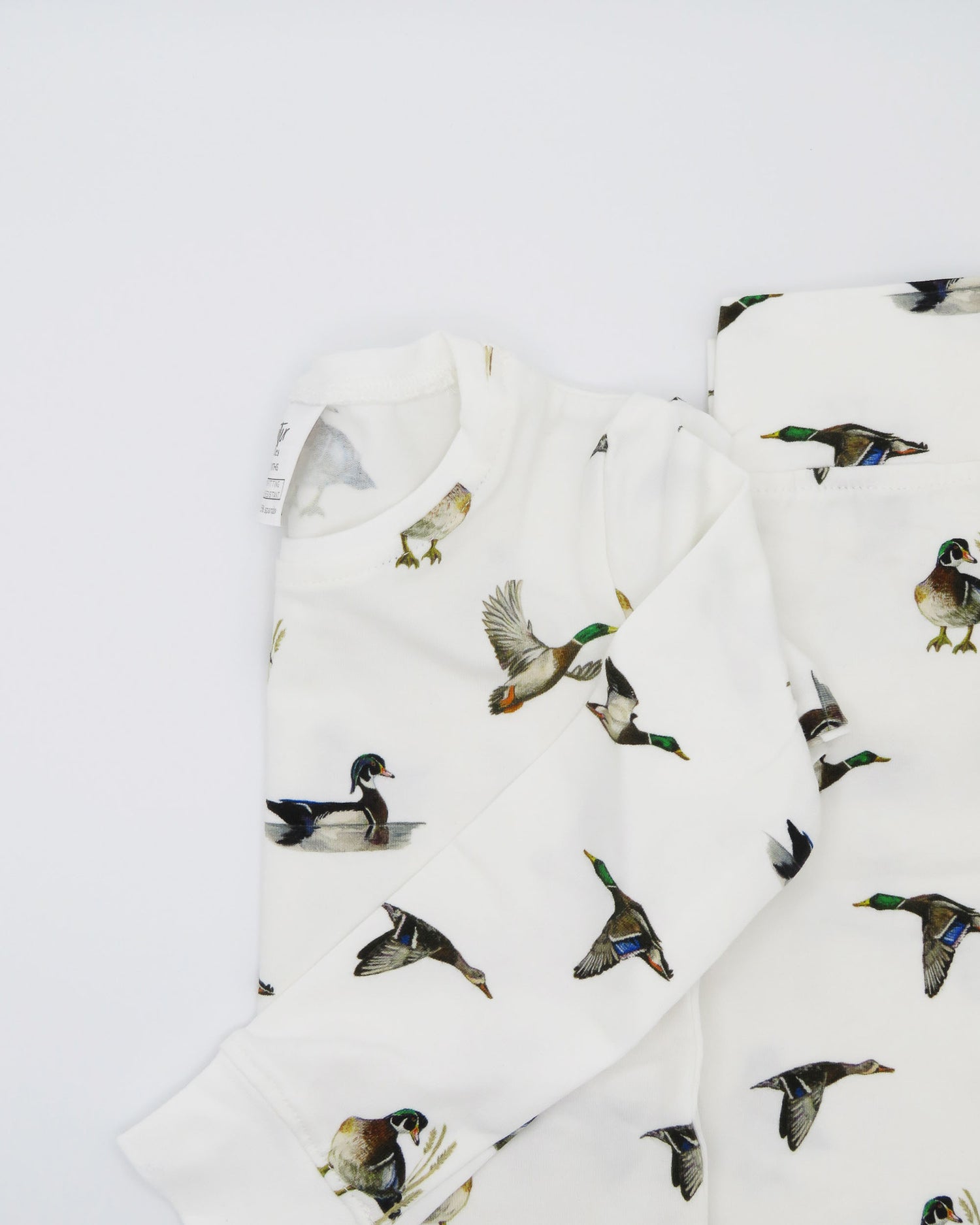Unisex loungewear or sleepwear featuring a Diving Ducks print on soft white fabric. Kids’ pajamas flat image. Perfect for both indoor and outdoor wear.