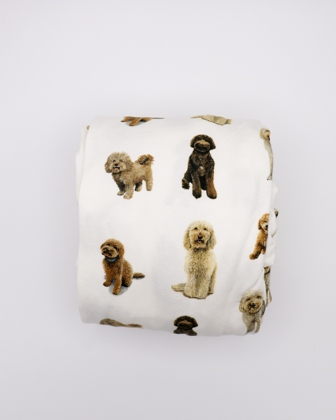 Fitted cotton crib sheet featuring an all-over goldendoodle dog pattern folded on a crisp white background.