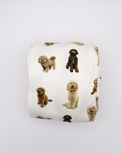 Fitted cotton crib sheet featuring an all-over goldendoodle dog pattern folded on a crisp white background.