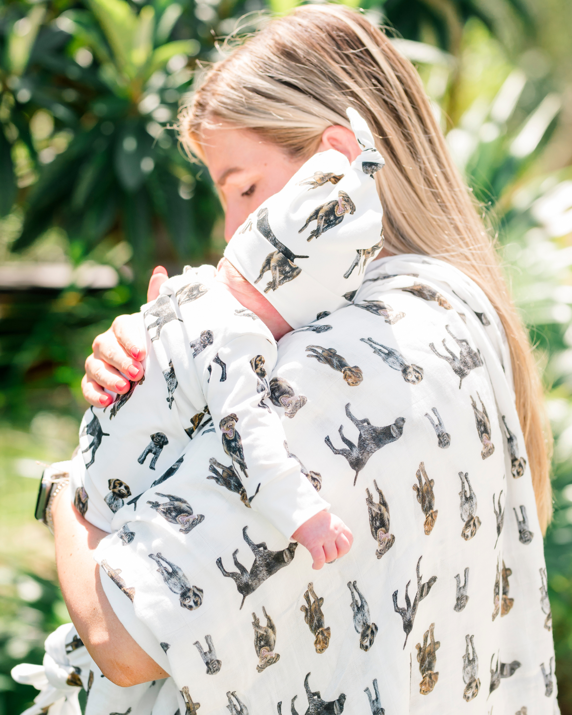 Unisex baby swaddle blanket featuring German Wirehaired Pointers printed on soft white fabric, ideal for newborn comfort and nursery use. Used by a mom with her baby outdoors.