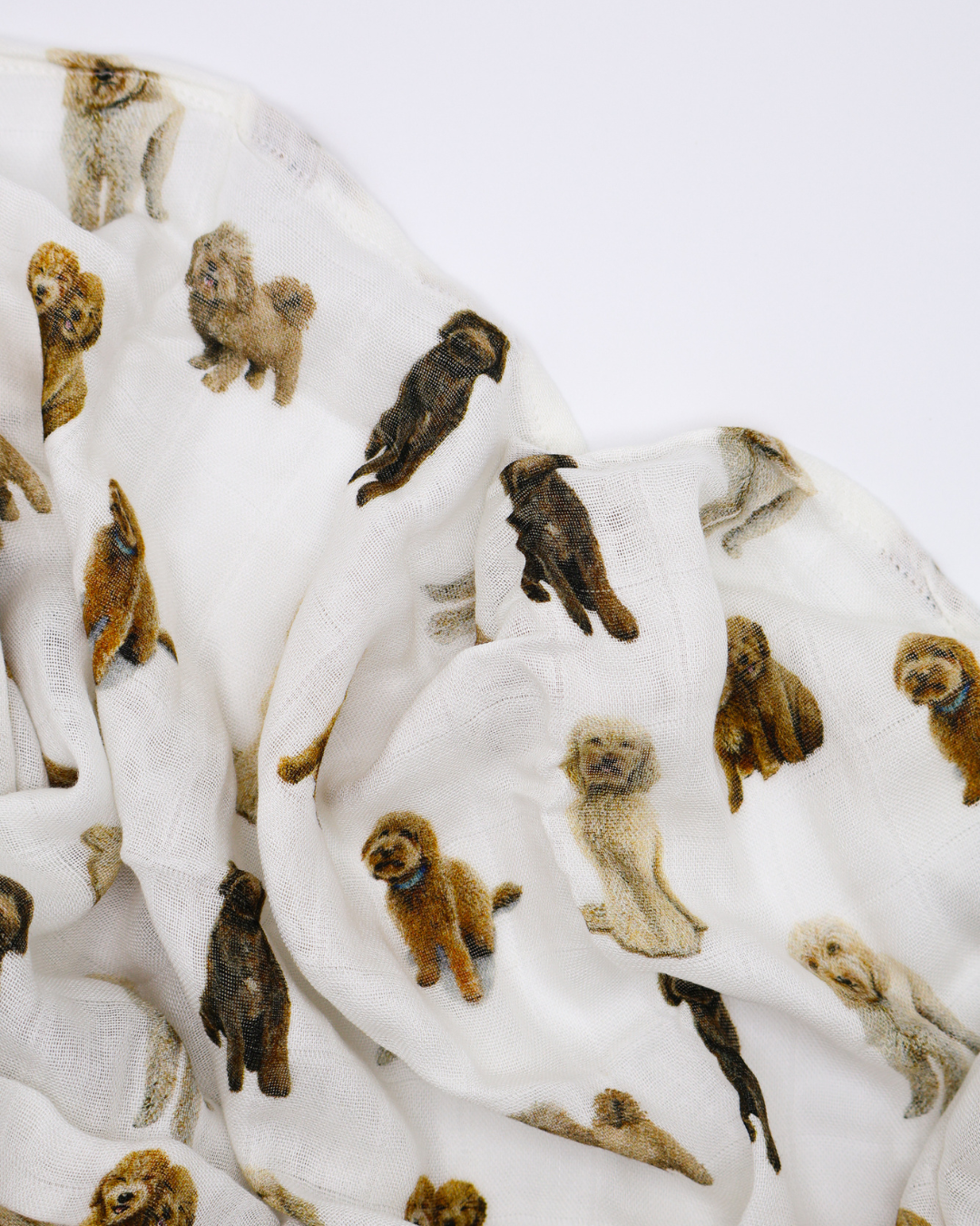 Flat-lay of an unfolded muslin baby swaddle blanket covered in realistic sitting and standing goldendoodle dog pattern.