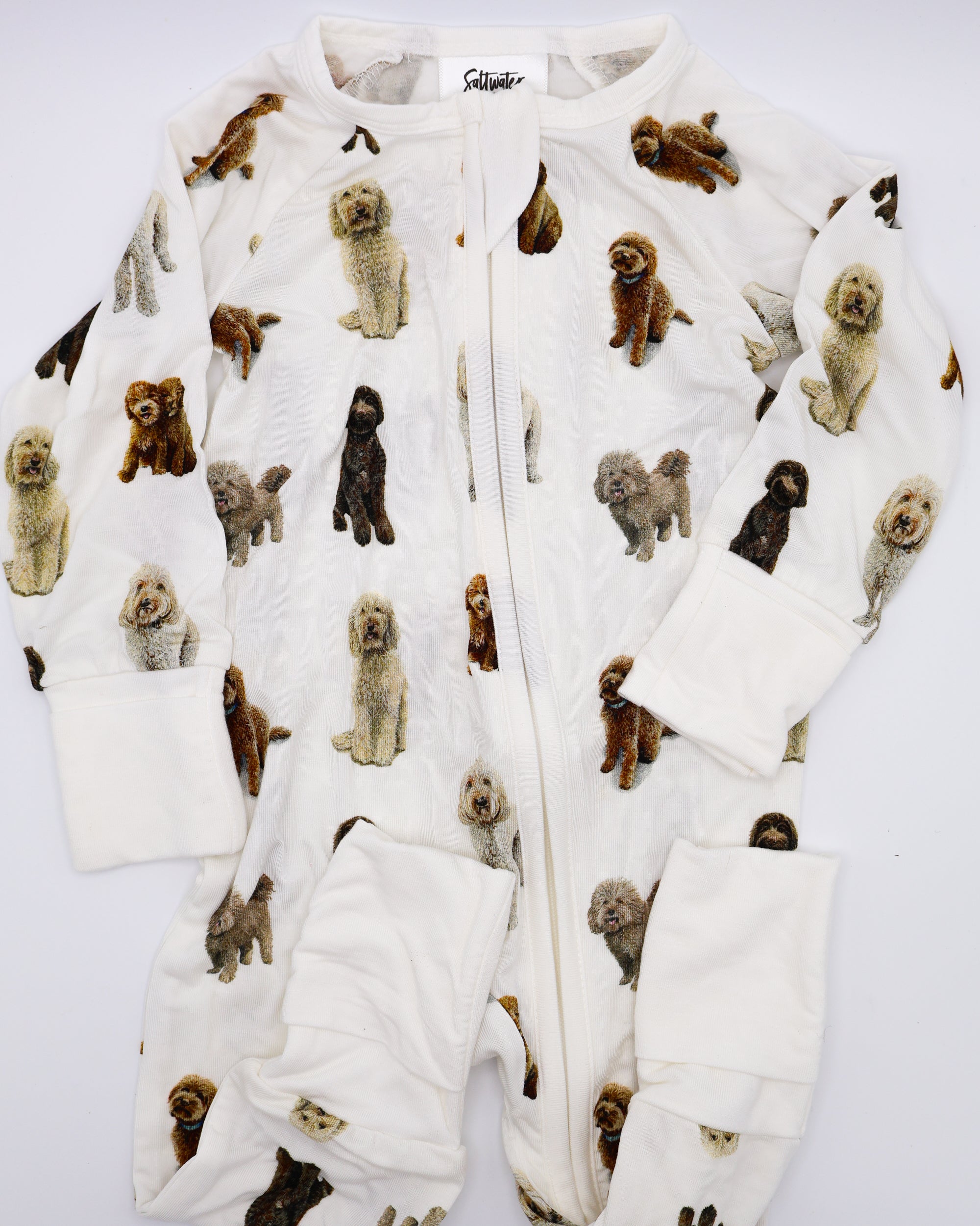 Flat-lay view of a long-sleeve goldendoodle pattern convertible zip footies, a baby romper with two-way zipper and convertible fold-over feet.