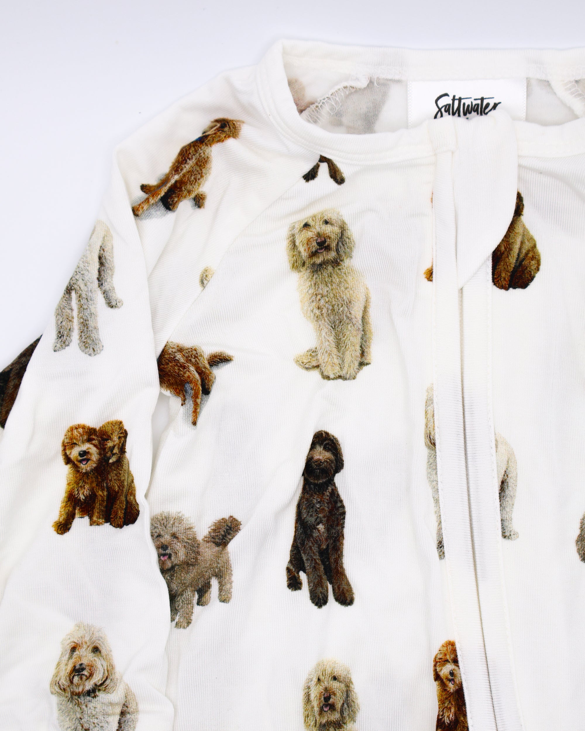 Close-up of a flat-lay view of a long-sleeve goldendoodle pattern convertible zip footies, a baby romper with two-way zipper and convertible fold-over feet.