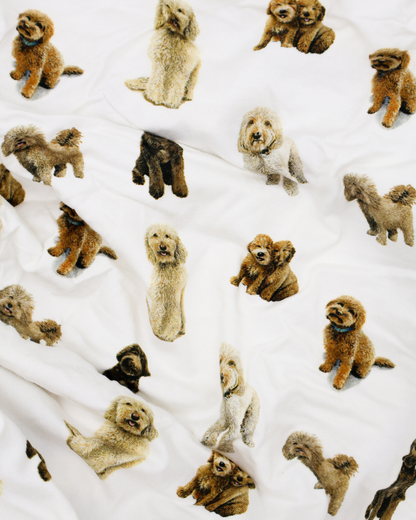 Fitted cotton crib sheet featuring an all-over goldendoodle dog pattern on a crisp white background.