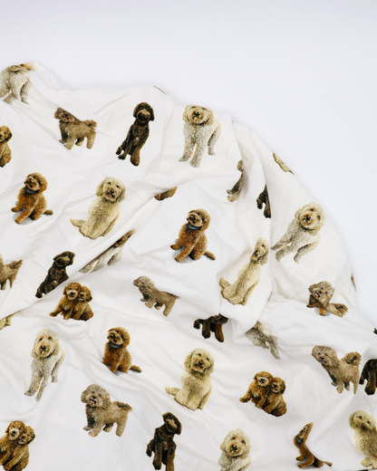 Fitted cotton crib sheet featuring an all-over goldendoodle dog pattern on a crisp white background.