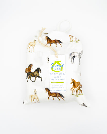 Our Harbor Horses crib sheet featuring hand-painted, colorful horses printed on soft white 100% cotton jersey, fitted for cribs or toddler beds, perfect for a horse-themed nursery.