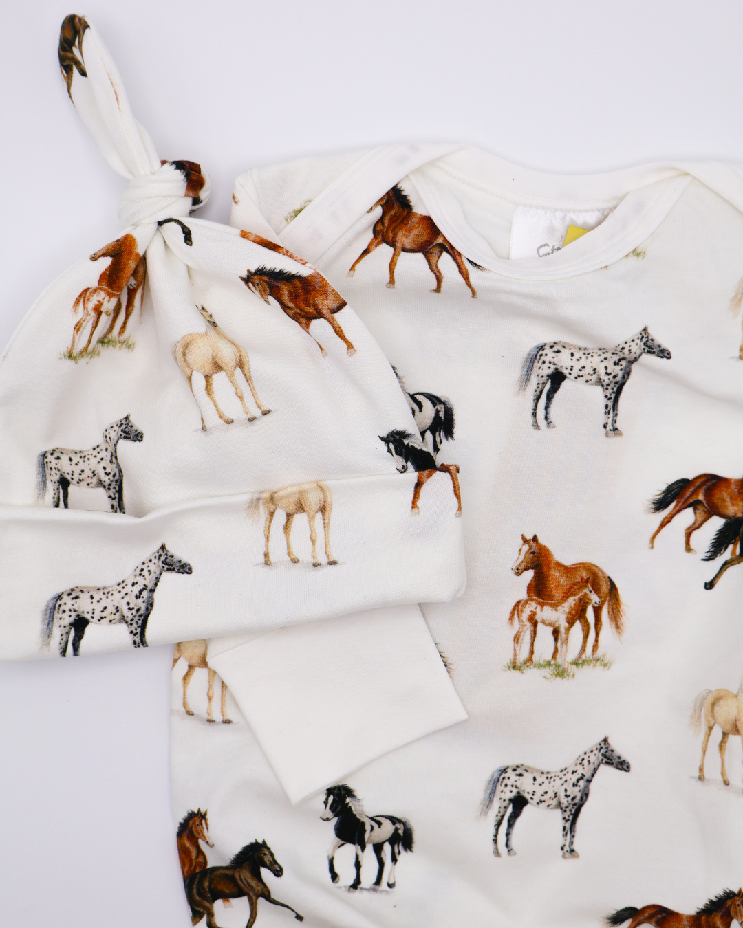 Harbor Horses Newborn Gown and Hat set printed on soft white fabric, featuring a charming harbor horses pattern. This cozy newborn outfit includes a matching hat and gown, making it a newborn’s new favorite and a perfect addition to your hospital bag.