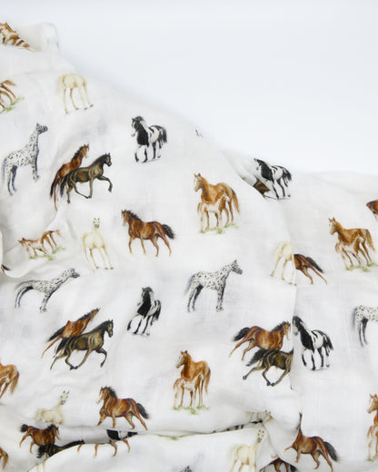 Harbor Horse swaddle with painted horse designs, made of soft white 30% organic cotton and 70% bamboo, perfect for wrapping a newborn and adding to a hospital bag.