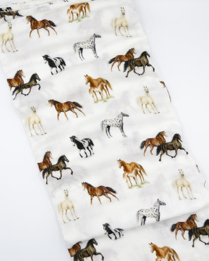 Harbor Horse swaddle with painted horse designs, made of soft white 30% organic cotton and 70% bamboo, perfect for wrapping a newborn and adding to a hospital bag.