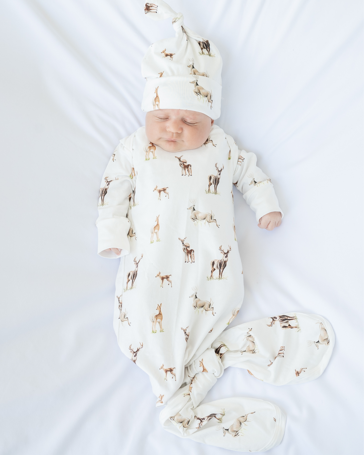 Little Fawn Big Yawn Deer newborn gown and matching hat, made from soft white cotton jersey with bottom flaps for knotting, cozy and perfect for your hospital bag. Worn by a sleeping baby.